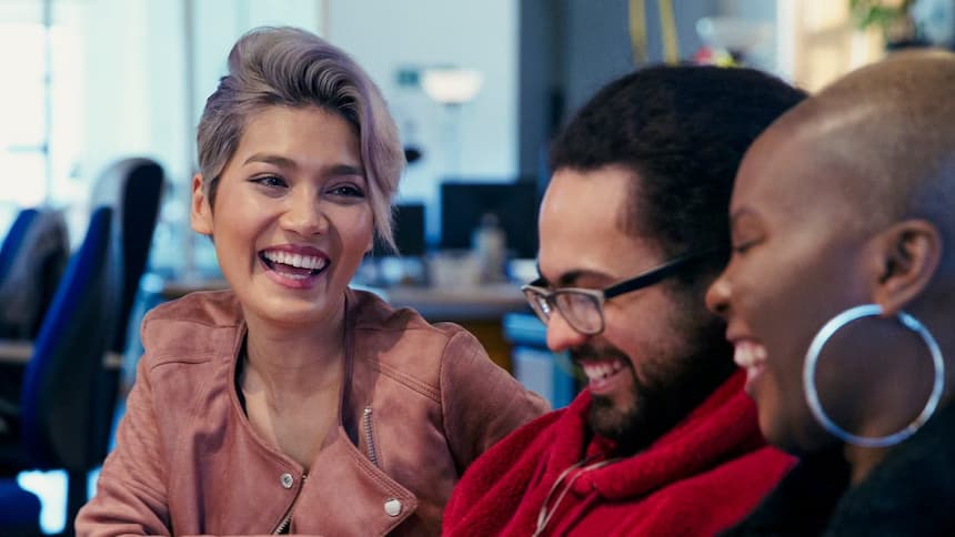 Three people sitting down and smiling 