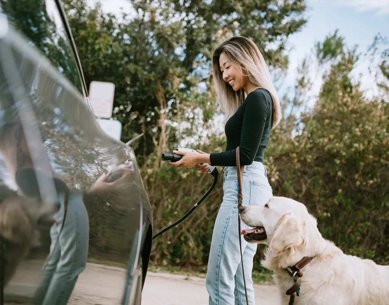 Woman charging EV standing next to her dog