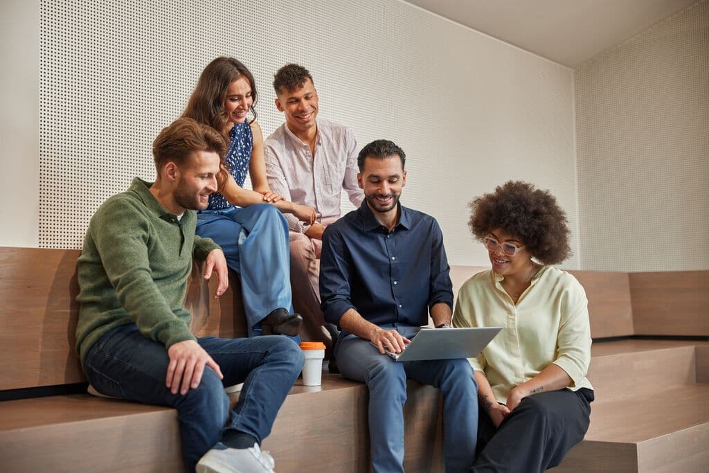 Colleagues smiling and looking at a laptop