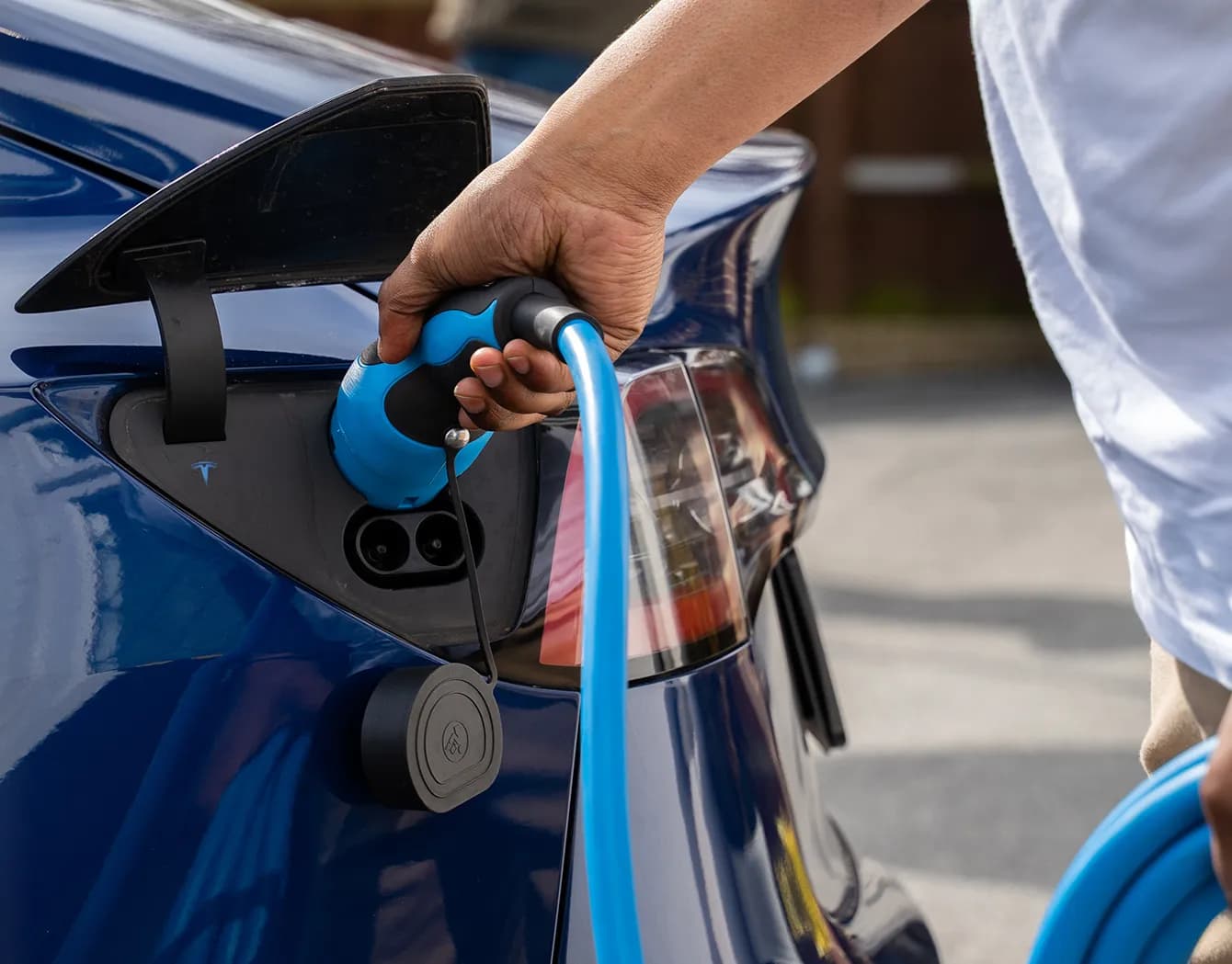 Close up of cable and nozzle connected to electric vehicle being charged.